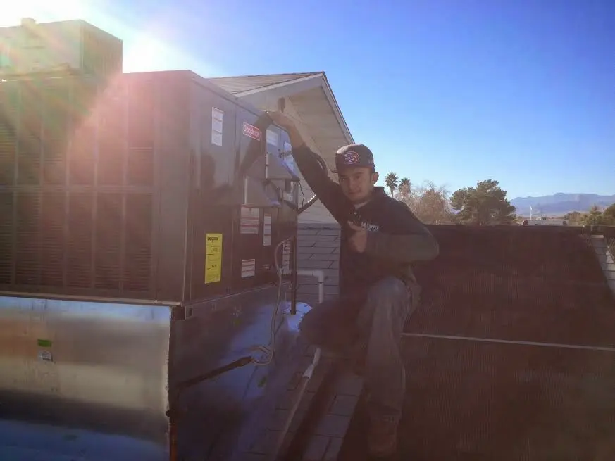 HVAC technician performing Air Duct Cleaning on a rooftop unit in Bend