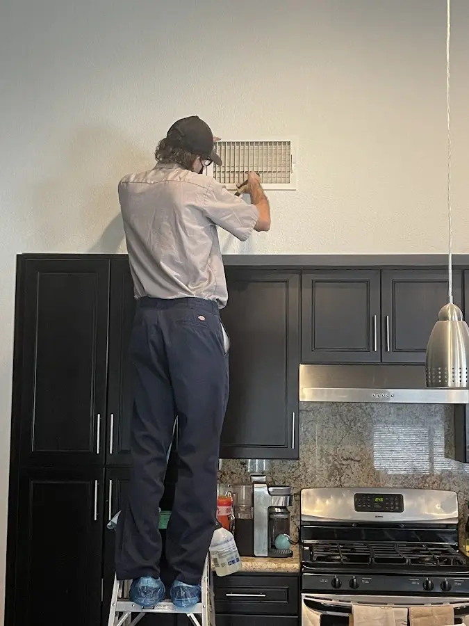 Technician inspecting an air vent during HVAC service in Bend